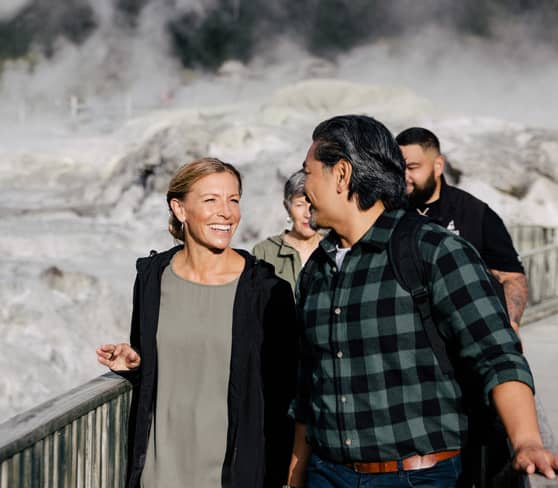 People walking by the steaming geysers in Rotorua, New Zealand.