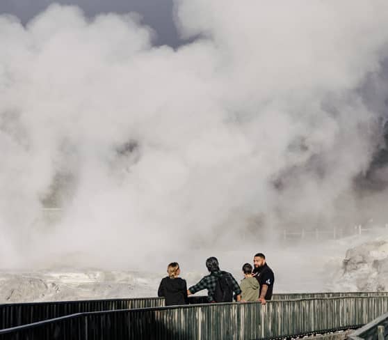 Visitors observing steam from a geyser in Rotorua.