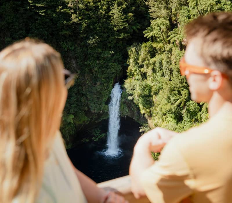 Couple looking at waterfall at green rainforest,