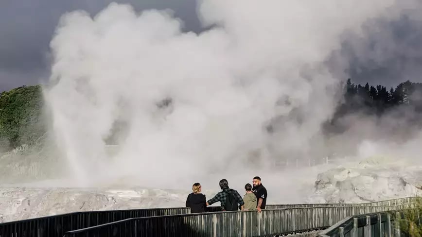 Visitors observing steam from a geyser in Rotorua.