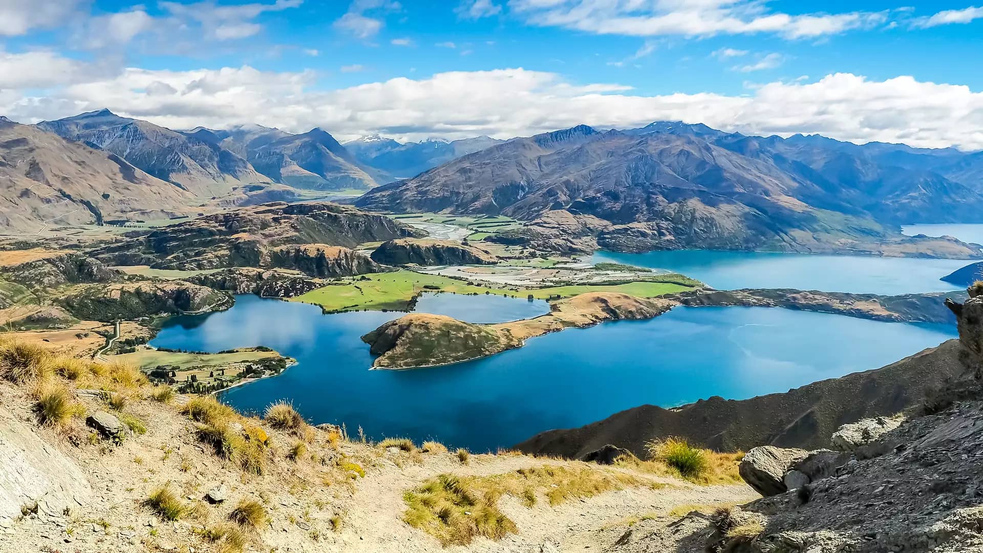 Panoramic view of Lake Wanaka with mountains and blue sky in the background.